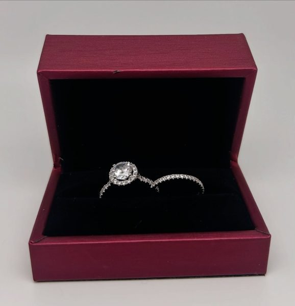 Bague solitaire en or blanc avec sa pierre centrale, dans un écrin bordeaux
